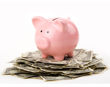 salvadenaio a forma maiale sopra mucchio di soldi
